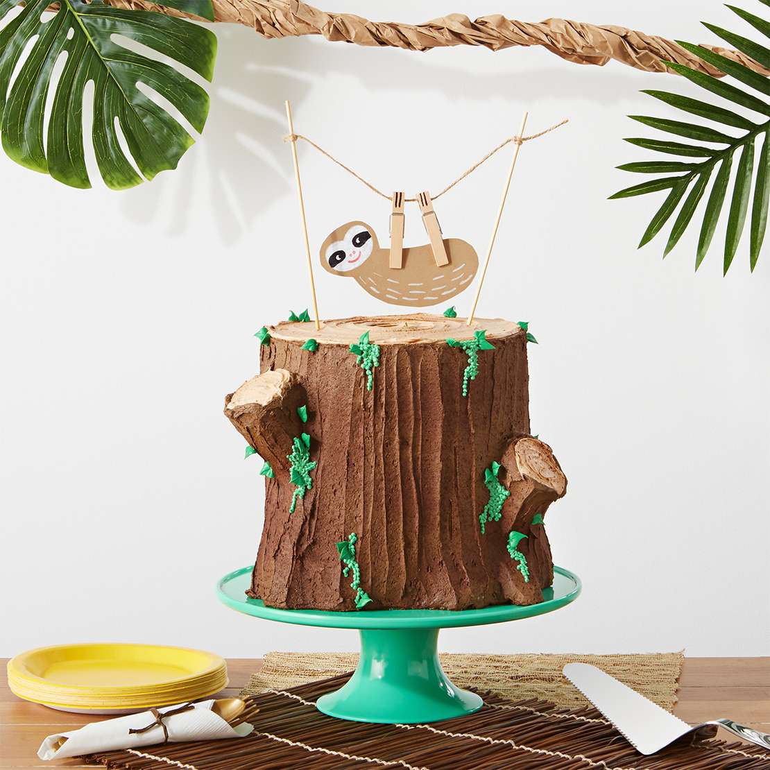 Sloth cake
Start by stacking four round cakes, adding buttercream frosting between each layer. Frost the whole thing in chocolate frosting, and add two larger globs of frosting for the tree nubs. With a spatula, frost upwards to create the indentations of tree bark. Then, take lighter brown frosting and frost the “exposed” part of the stump in a circular motion.

Tip: Mix green food coloring into the buttercream frosting for the moss and the leaves. For the moss, use circular piping tip #2. For the leaves, use tip #352.