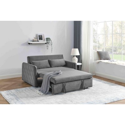 Grey upholstered sofa bed with chaise-style section and pull-out bed extended, in a bright room