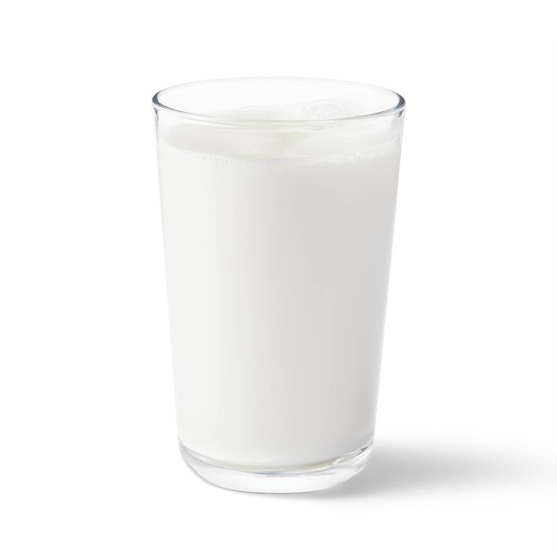 A clear glass filled with white colored liquid on a white background.