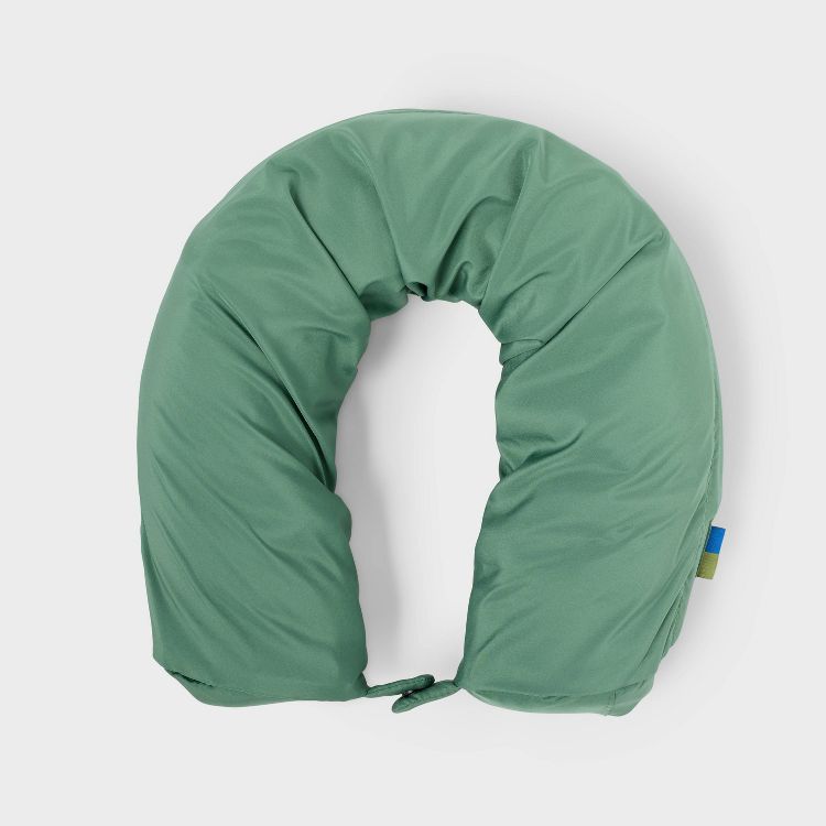 A green colored U-shaped neck pillow with a small blue and green tag on the side.