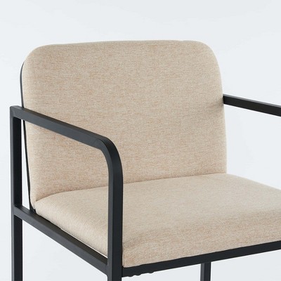 Close-up of beige upholstered bar stool with armrest