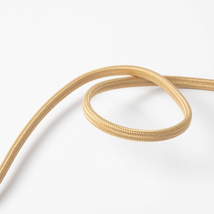 A coiled gold colored electrical cord on a white surface.