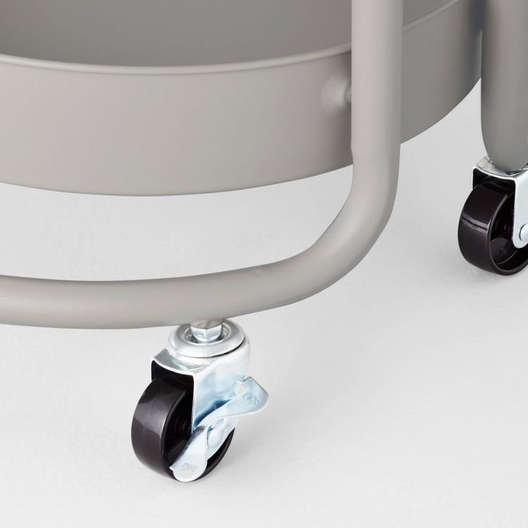 A gray colored utility storage cart with black wheels and metal frame.