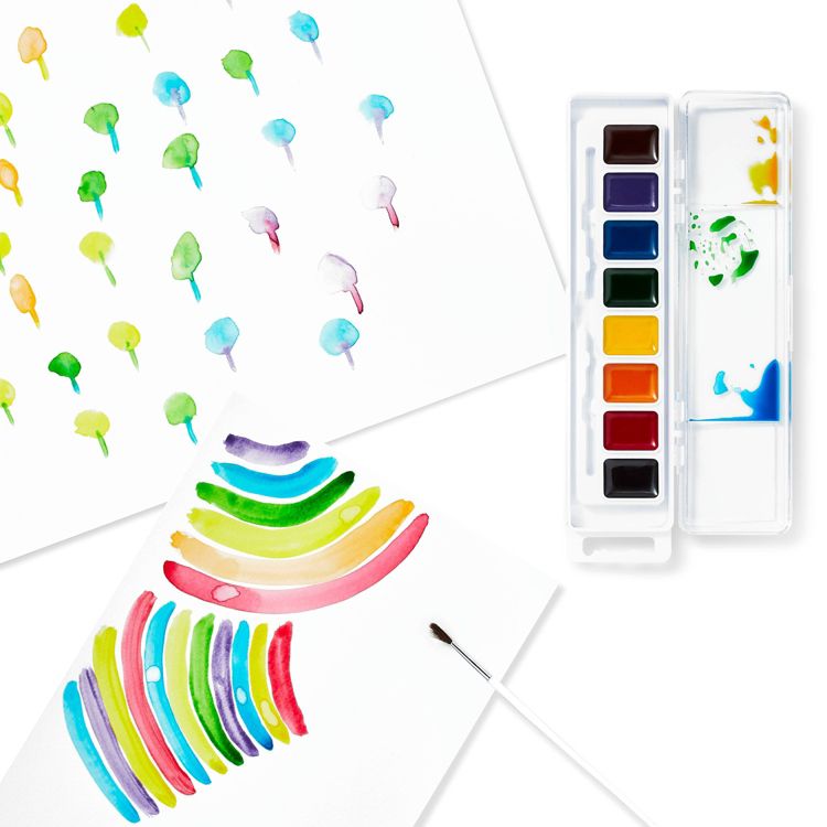 A watercolor paint set with eight colors in a plastic case, accompanied by two sheets of paper displaying colorful brush strokes and patterns.