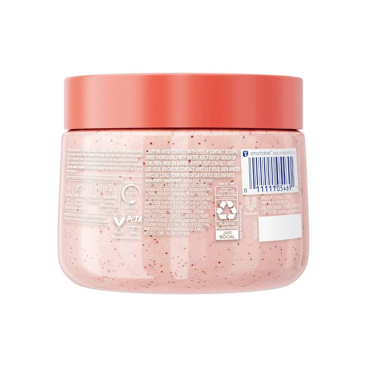 A plain shot of the back of Dove Body Scrub, White Peach & Crushed Rice. The packaging is a clear plastic jar with a coral-colored lid. Key claims include "PETA Cruelty-Free," "Paraben-Free," and "Made with 100% Natural Shea Butter." 