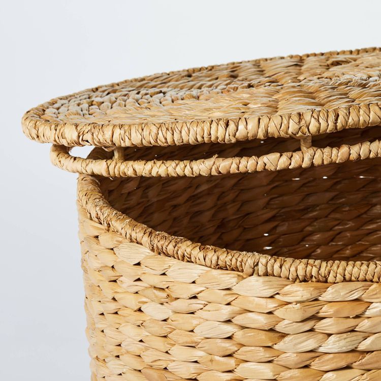 A woven natural colored ottoman with a partially open lid.
