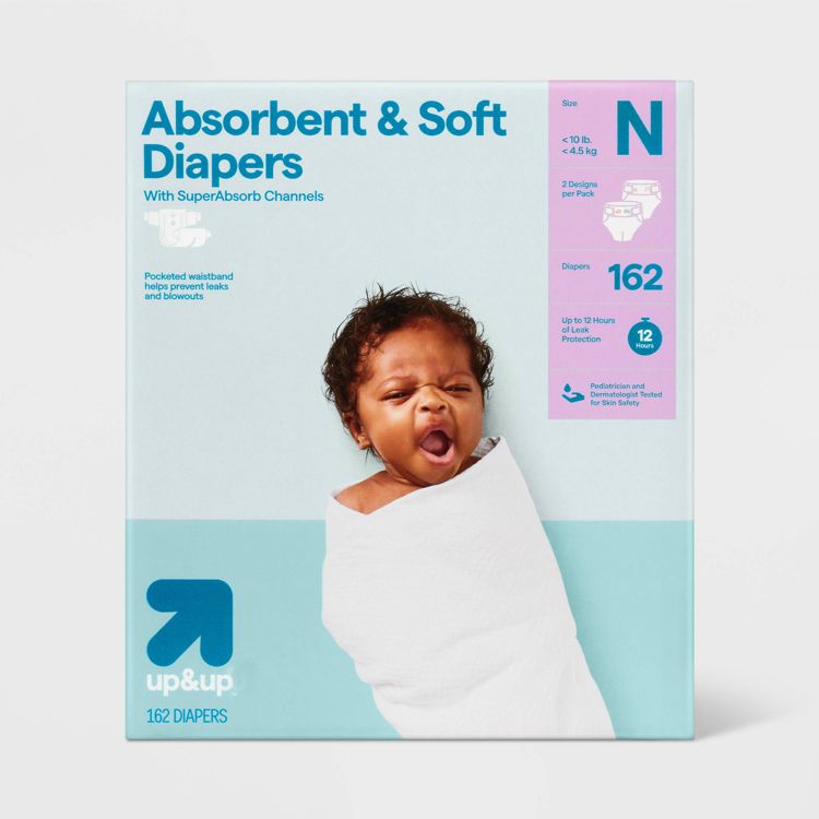 Packaging for "Absorbent & Soft Diapers" by up&up, featuring a baby wrapped in a white blanket, with details indicating size N for under 10 lb, 162 diapers, and up to 12 hours of leak protection.