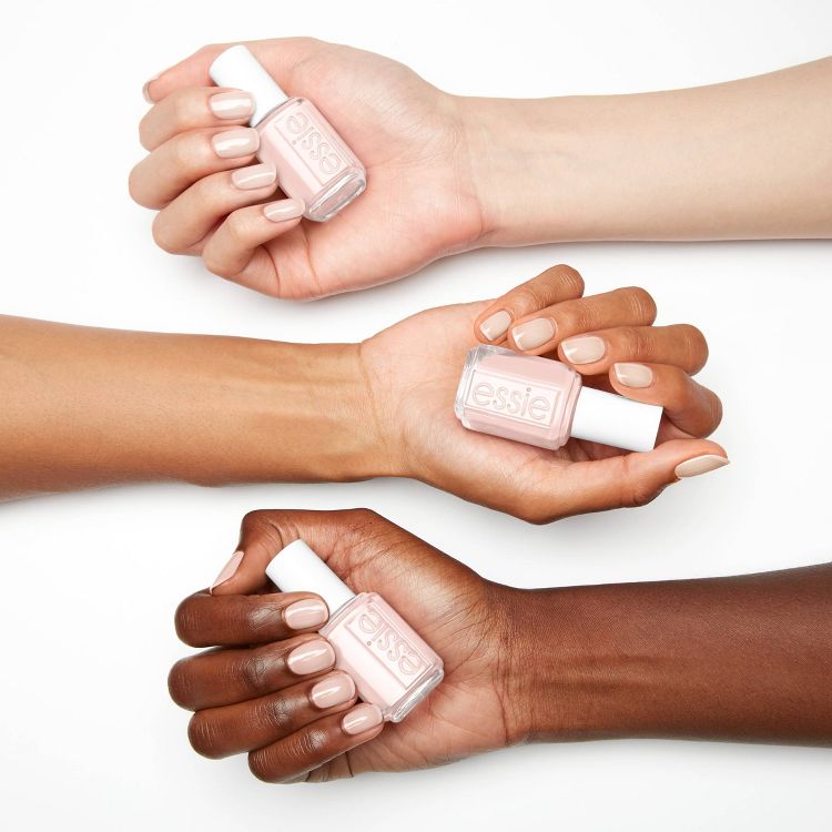 Three hands holding bottles of light pink colored nail polish with matching manicures.
