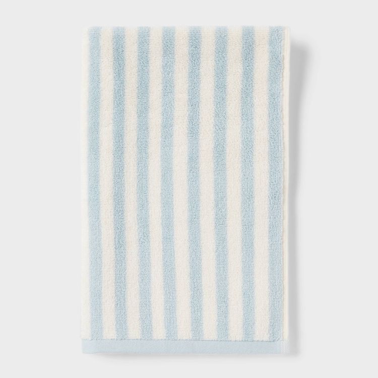 A folded towel with light blue and white colored vertical stripes.