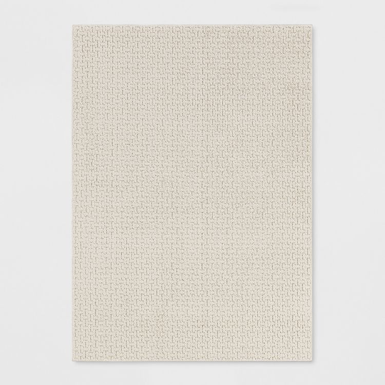 A rectangular beige colored rug with a subtle textured pattern.