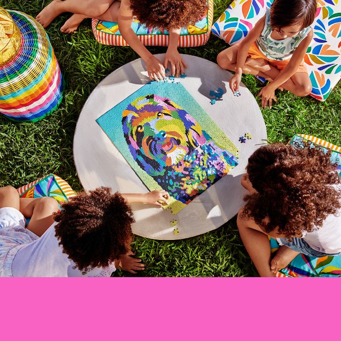 A group of kids playing outside with a colorful dog puzzle and outdoor cushions and pillows featuring a variety of bright prints.