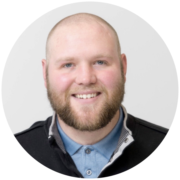 Joshua Leary, Target iOS Engineer, photographed against a plain gray background, smiling and wearing a black sweater over a blue button down shirt