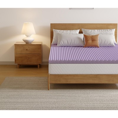 Perspective of bed with lavender topper and nightstand
