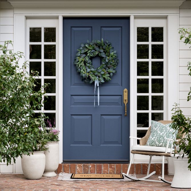 Inviting front door with rocking chair and various potted plants