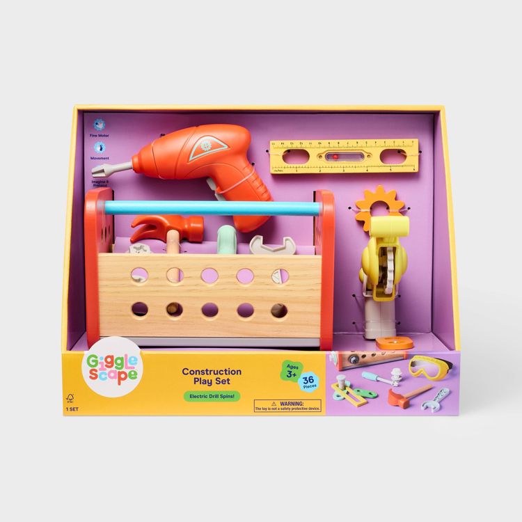 A colorful construction play set for ages 3 and up, featuring a red toy drill, wooden toolbox, and various tools, with a label indicating 36 pieces.