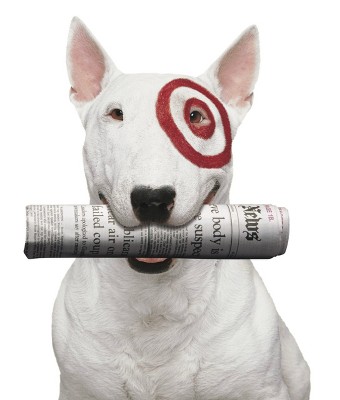 Target mascot Bullseye, a white bull terrier with a red Target logo painted around his eye, with a rolled up newspaper in his mouth