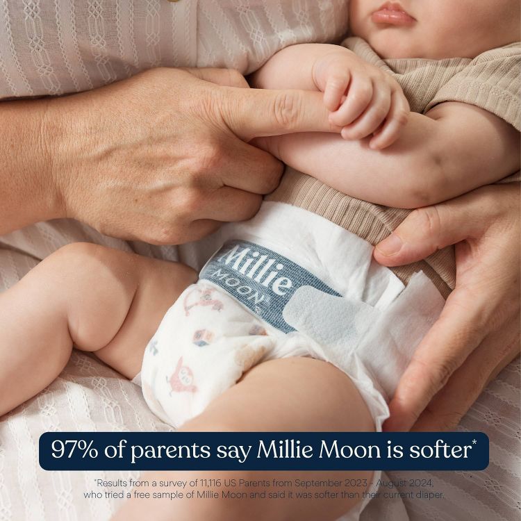 A baby wearing a diaper with "Millie Moon" text visible, held by an adult.