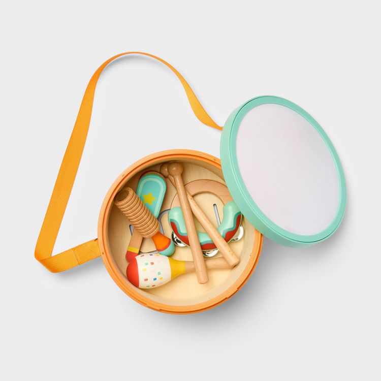 A round orange and teal colored drum case containing various small wooden percussion instruments with an orange strap.