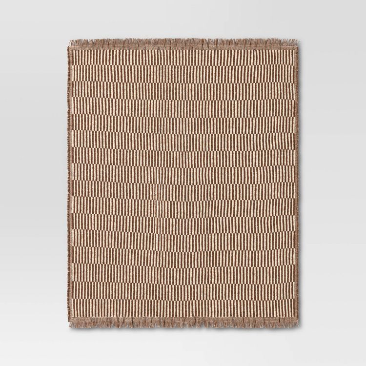 A beige and brown colored blanket with a striped pattern and fringed edges.