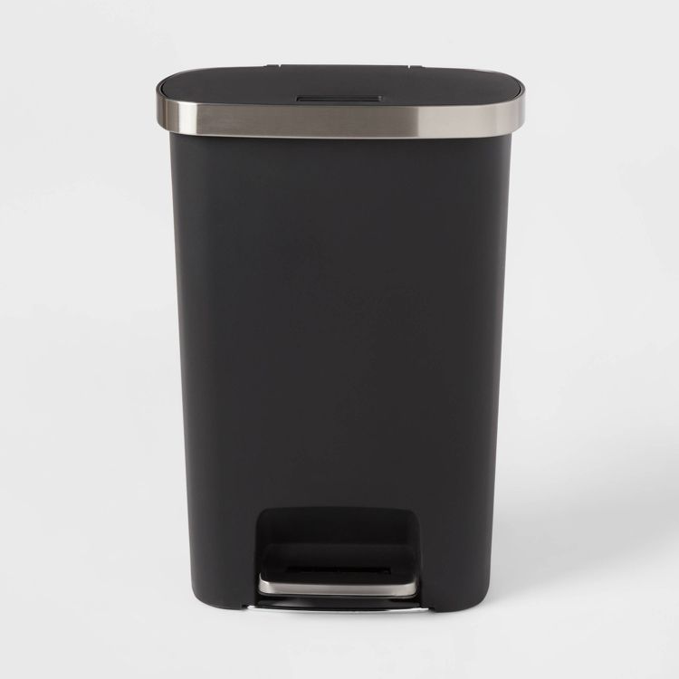 A black colored indoor trash can with a silver colored lid and foot pedal.
