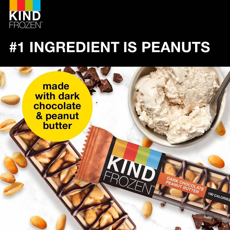 A KIND FROZEN bar with dark chocolate and peanut butter, surrounded by peanuts and chocolate pieces, next to a bowl of ice cream.
