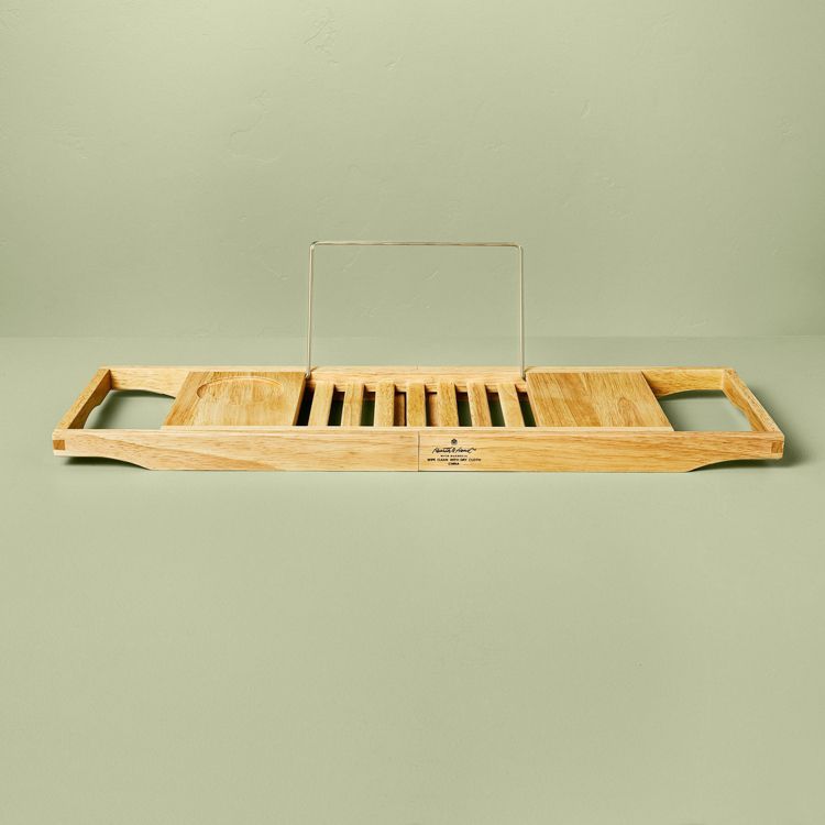 A wooden bath tray with slatted design, handles on each side, and a metal book holder in the center.