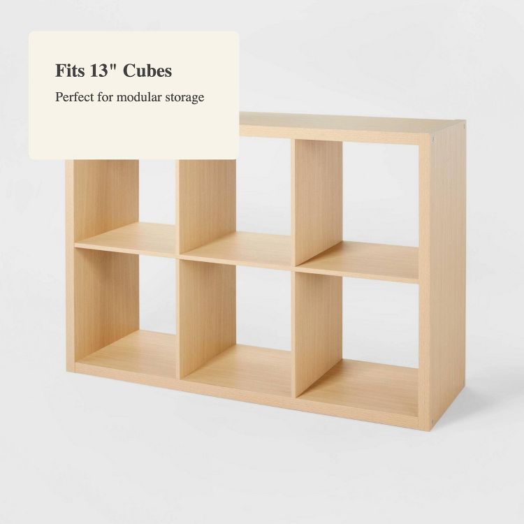 A light wood colored bookshelf with six open square compartments, labeled "Fits 13" Cubes" and "Perfect for modular storage."