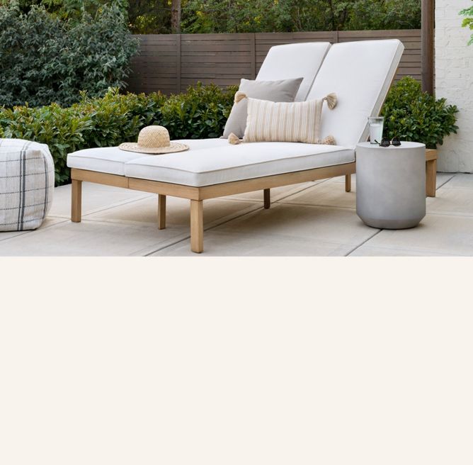 Outdoor space with double wide chaise lounge, side table and pouf.