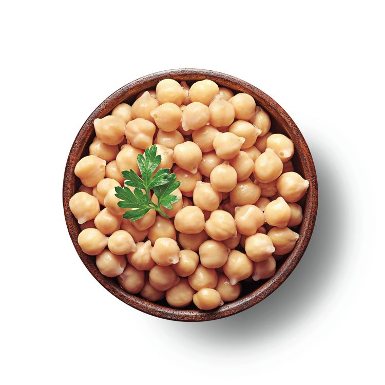 A wooden bowl filled with chickpeas and garnished with a sprig of parsley on top.