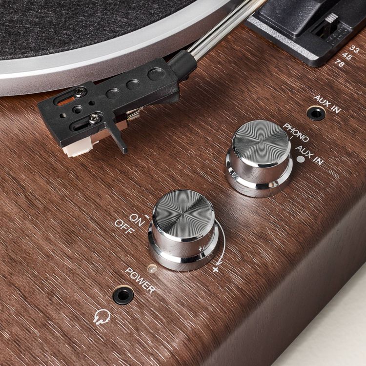 A turntable with a wooden finish featuring a tonearm, two silver colored control knobs, and labeled inputs for phono and aux.