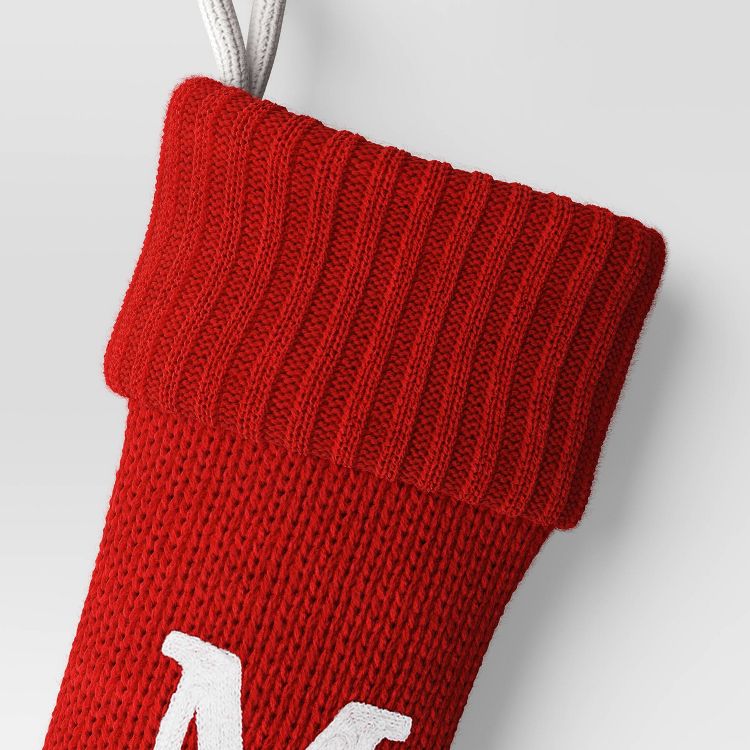 Red colored knitted stocking with a white letter "M" and a white hanging loop.