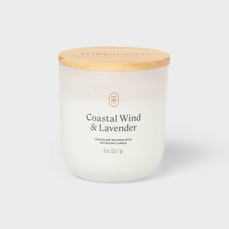 White colored candle in a frosted glass jar with a wooden lid, labeled "Coastal Wind & Lavender" and "8 oz (226.7 g)."