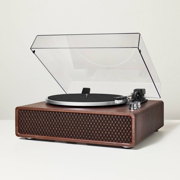 A turntable with a wooden base, black platter, and clear dust cover, featuring a tonearm and control knobs.