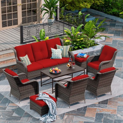 Red-cushioned wicker seating arrangement on a patio with plant background