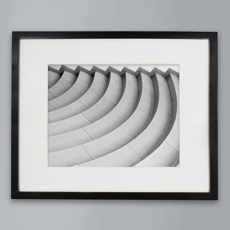 A black colored frame with a black and white photo of curved steps on a light gray background.