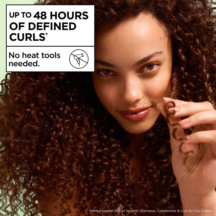 A person with defined curly hair holds a curl, with text stating "Up to 48 hours of defined curls" and "No heat tools needed."