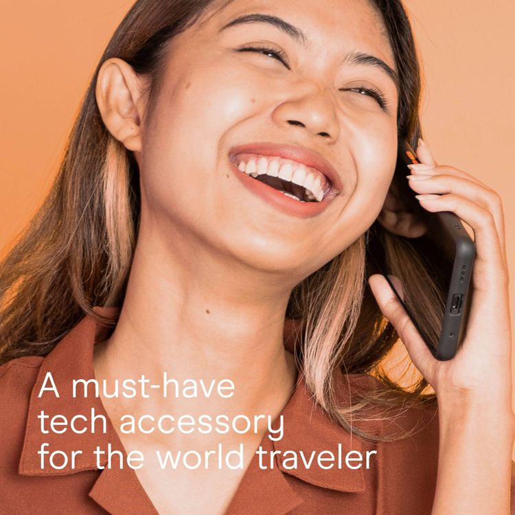 A person holding a black colored adapter with visible ports against an orange background, accompanied by the text "A must-have tech accessory for the world traveler."