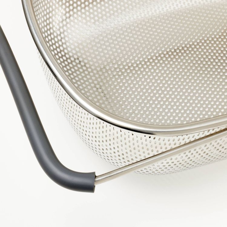 A silver colored perforated colander with a black colored handle.