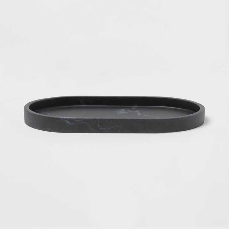 A black colored oval tray with a smooth surface and slightly raised edges.