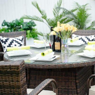 Close-up of round glass table with place settings and center vase
