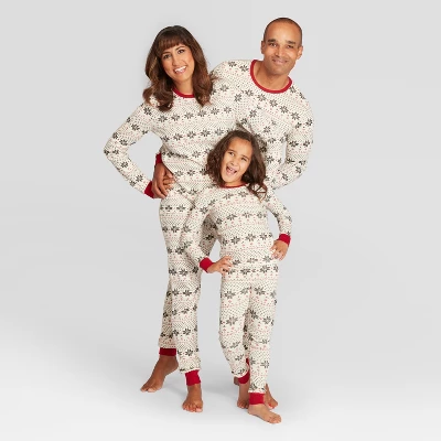 An image of a man, woman, and child wearing beige pjs with snowflakes on them.
