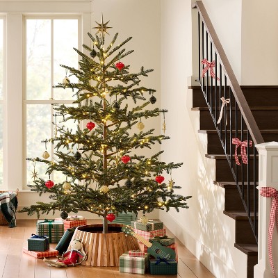 A gold colored star topper is placed on top of a decorated Christmas tree with lights and ornaments.