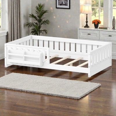 White wooden kids bed frame with guard rail and open slats, placed in a room