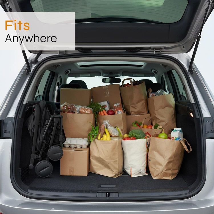 A folded black colored stroller is placed in the trunk of a car alongside several grocery bags.