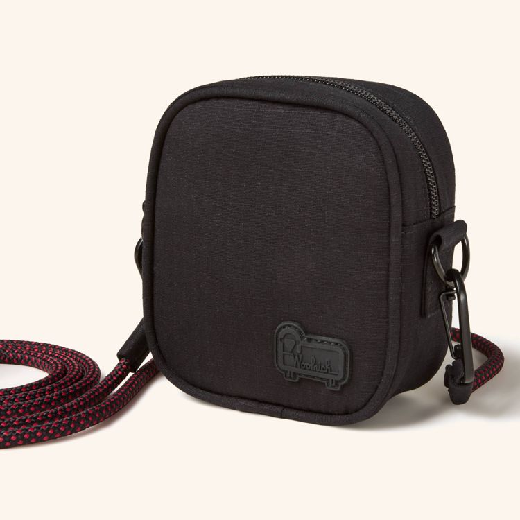 A black colored binocular case with a zipper and a red and black strap attached.