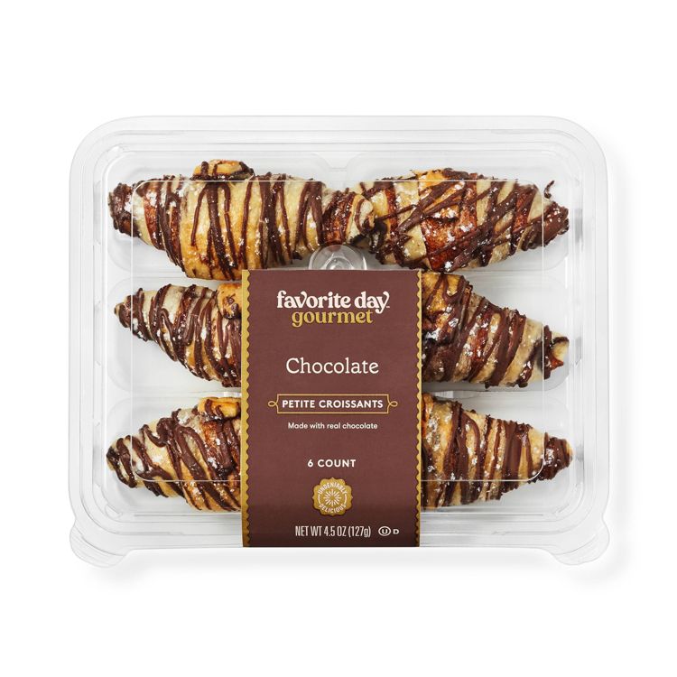 A clear plastic container holding six chocolate drizzled petite croissants with a label reading "favorite day gourmet Chocolate PETITE CROISSANTS Made with real chocolate 6 COUNT NET WT 4.5 OZ (127g)."