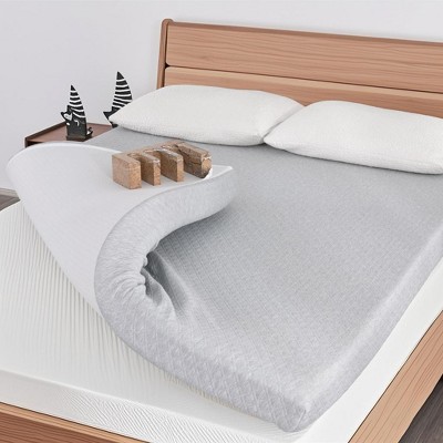 Close-up of rolled edge of a gray mattress with white cover and small wooden blocks