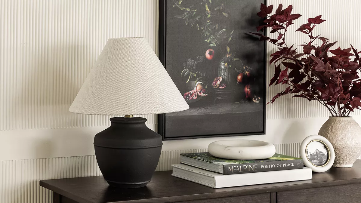 Moody console table featuring fall foliage, dark art and black ceramic table lamp 