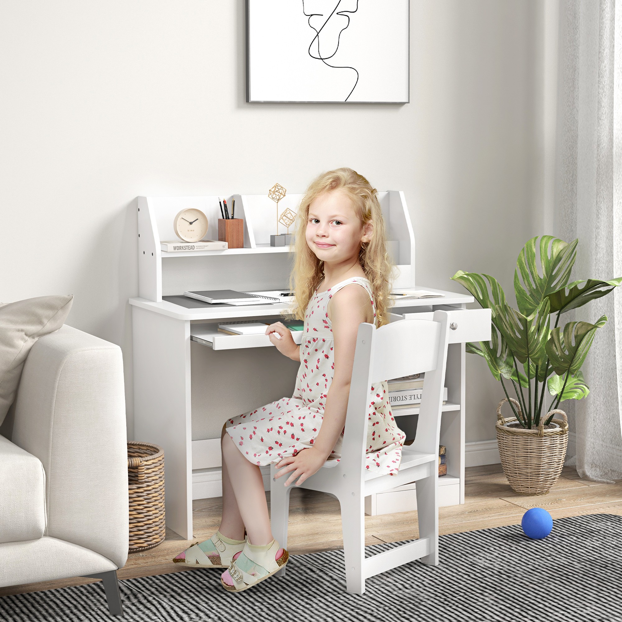 A young girl sitting at the white Qaba Kids Desk and Chair Set.