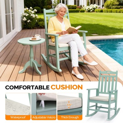 An elderly person sitting in a mint green rocking chair on a patio